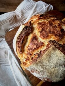 Rustic sourdough boule with a crackly scored crust on a wooden board.
