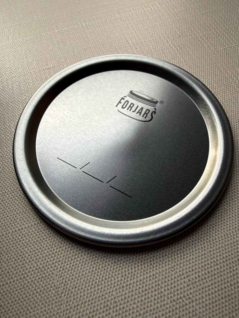Close-up of a ForJars canning lid on a linen surface
