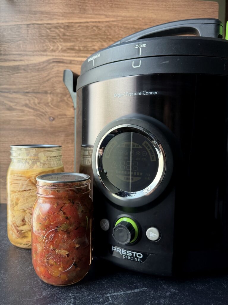 Presto Precise digital pressure canner with its display and control dial, next to jars of home-canned salsa