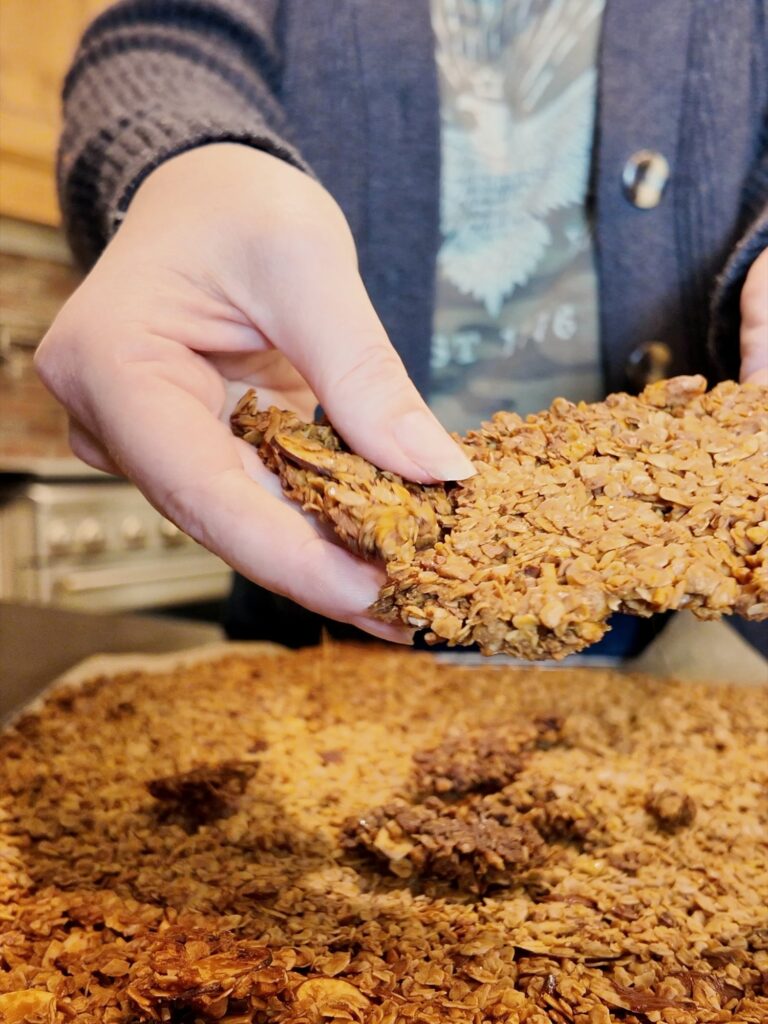 Breaking a large cluster off the cooled sheet of baked granola.