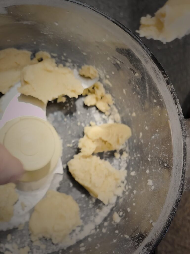 Chunks of butter-and-flour paste in a food processor bowl around the metal blade