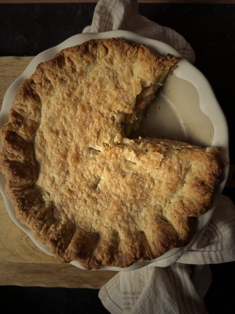 Chicken pot pie with one slice removed, showing creamy filling under the flaky all-butter crust