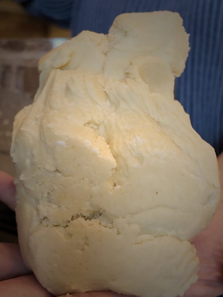 Hands holding a gathered, slightly rough mound of all-butter pie dough