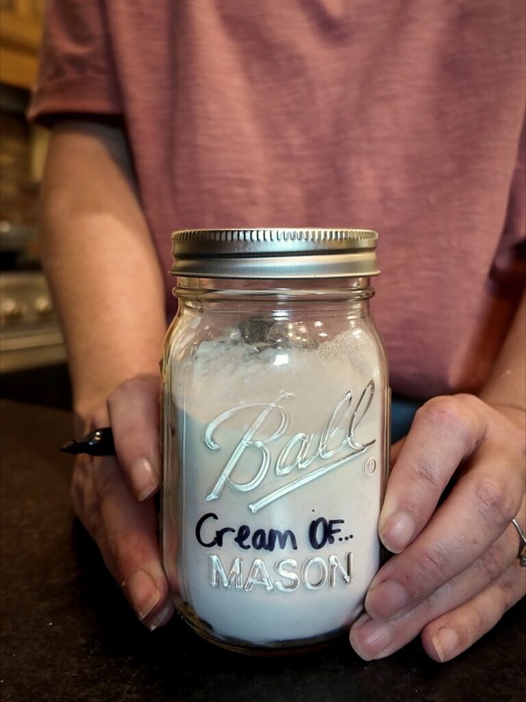Hands holding a Ball jar of dry mix labeled Cream Of