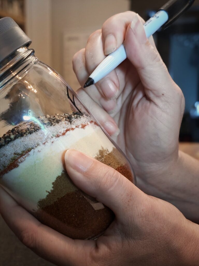 Labeling a jar of layered fajita seasoning spices with a marker
