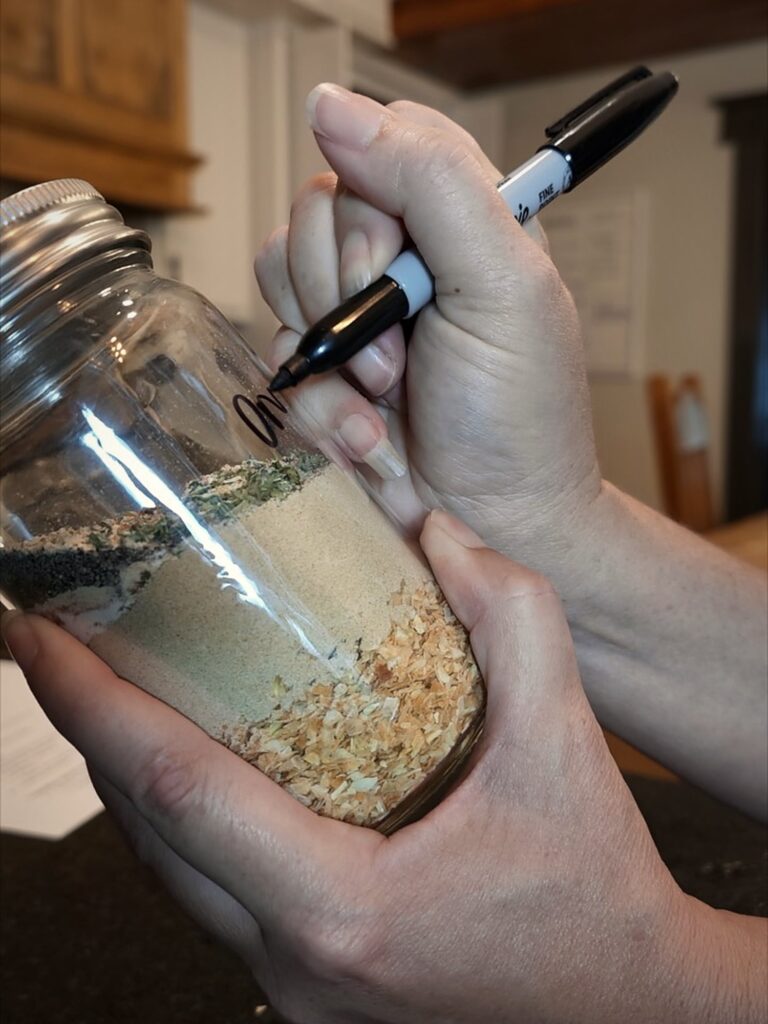 Writing on a jar of layered homemade onion soup mix with a black marker