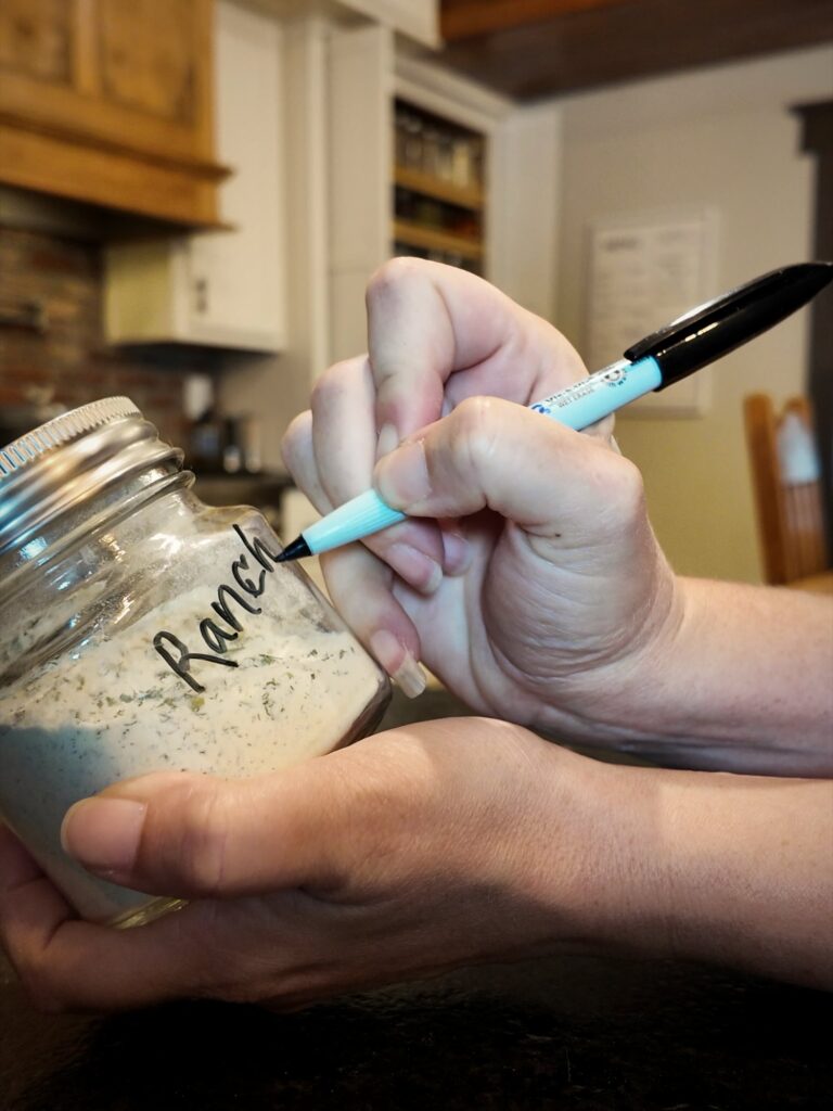 Writing a ranch label on a jar of homemade ranch seasoning mix with a marker