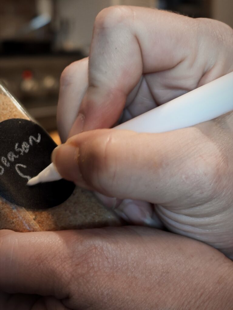 Writing a label on a spice jar of seasoned salt with a white marker