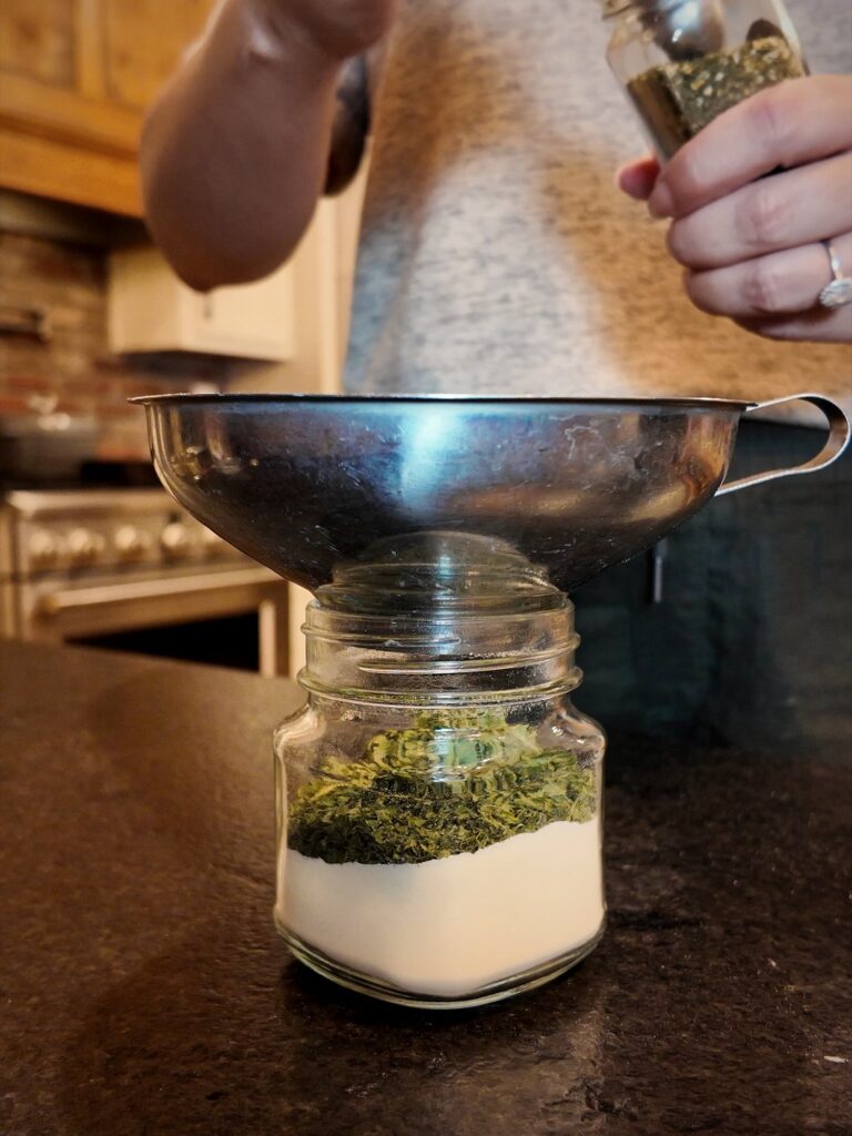 Ingredients for homemade ranch seasoning mix layered in a glass jar