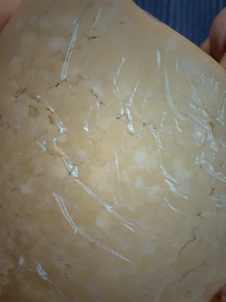 Disk of pie dough wrapped in cling wrap, with flecks of butter visible in the dough