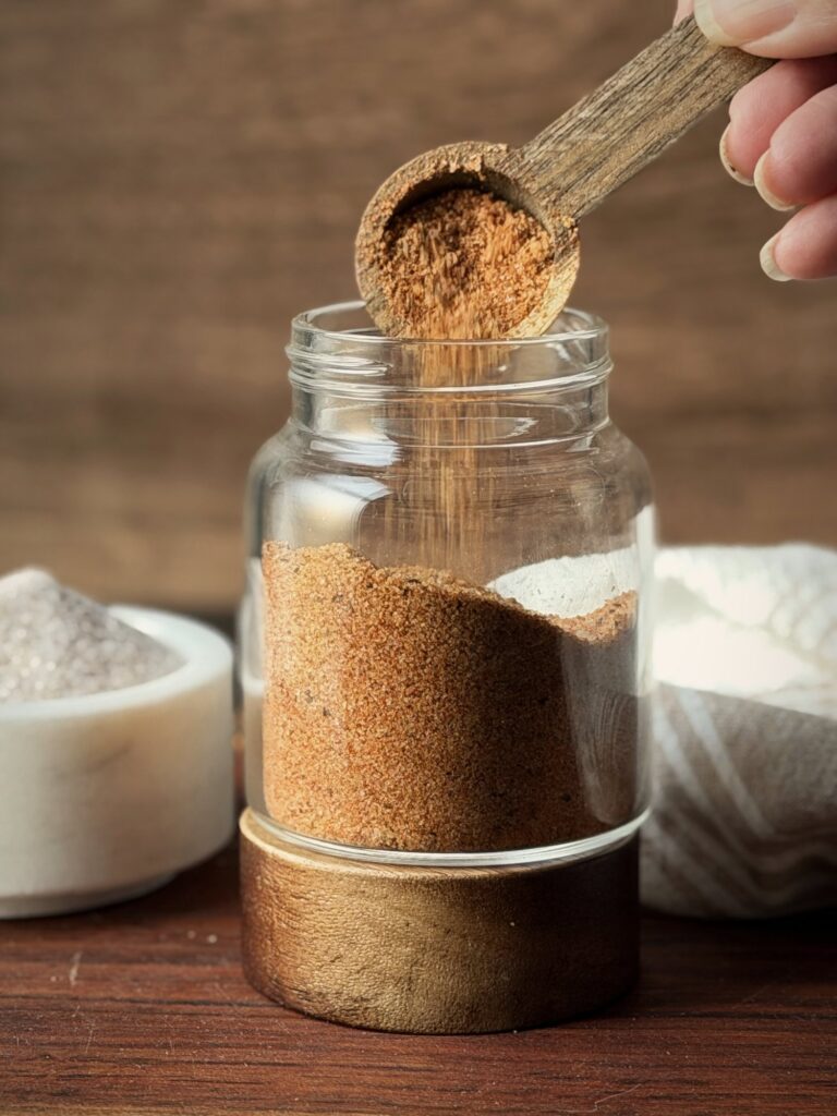Wooden scoop pouring seasoned salt into a glass jar