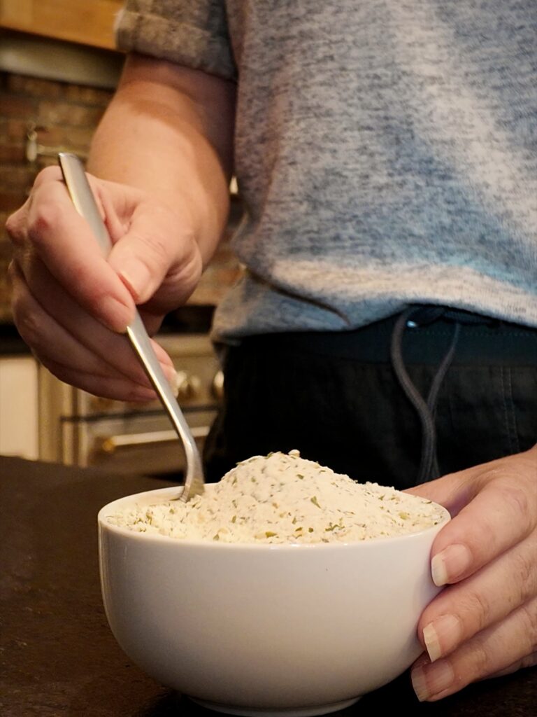 Stirring homemade ranch seasoning mix in a white bowl with a spoon