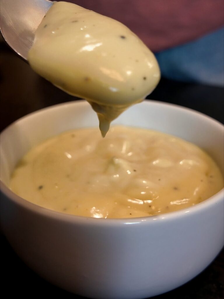 Spoonful of thick homemade cream soup held over a white bowl